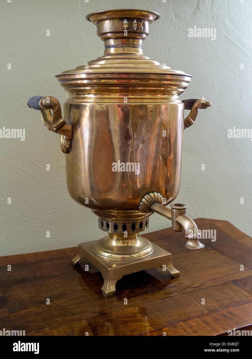 Old Russian tea brewing samovar standing on wooden tea table Stock Photo