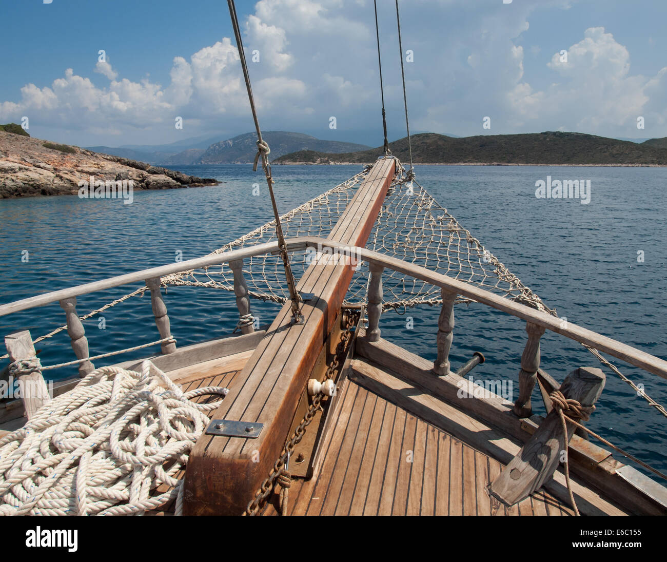the bow of a traditional wooden boat with teak deck, hardwood bowsprit withislands and hills Stock Photo