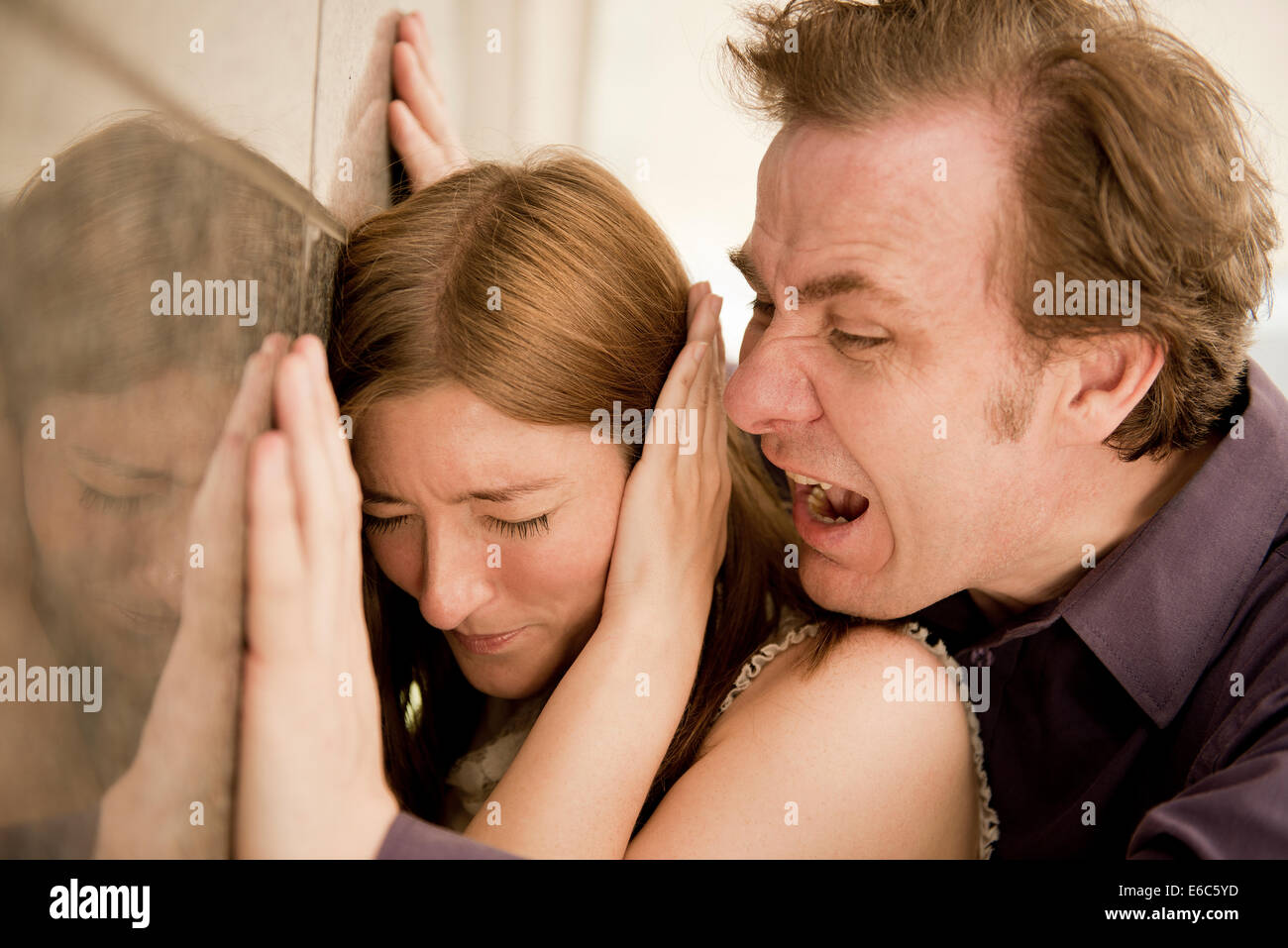 Angry man shouting and being threatening against a helpless woman. Stock Photo
