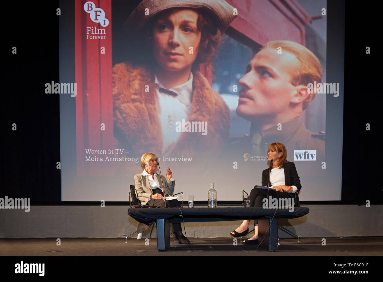 London, England, UK, 19 August 2014. Legendary BAFTA-Award winning multi-camera television drama director Moira Armstrong (L) being interviewed by Francine Stock (R) at an event in Miss Armstrong's honour organised by the British Film Institute (BFI) in association with BAFTA and Women in Film & Television (WFTV). The background slide is a still from Moira Armstrong’s 1979 BBC production ‘Testament of Youth’, an adaptation of Vera Brittain’s classic memoir about the impact of World War I. Credit:  John Henshall / Alamy Live News PER0421 Stock Photo