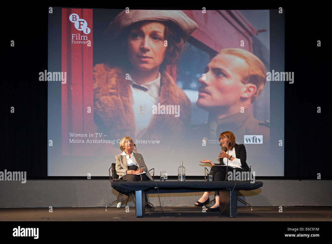 London, England, UK, 19 August 2014. Legendary BAFTA-Award winning multi-camera television drama director Moira Armstrong (L) being interviewed by Francine Stock (R) at an event in Miss Armstrong's honour organised by the British Film Institute (BFI) in association with BAFTA and Women in Film & Television (WFTV). The background slide is a still from Moira Armstrong’s 1979 BBC production ‘Testament of Youth’, an adaptation of Vera Brittain’s classic memoir about the impact of World War I. Credit:  John Henshall / Alamy Live News PER0422 Stock Photo