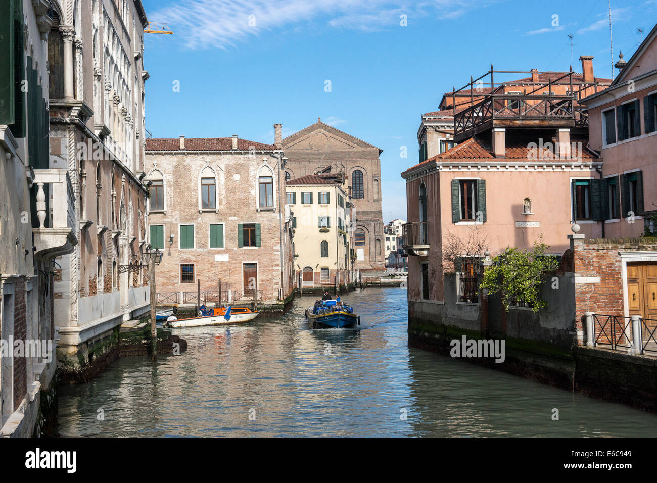 Work boats navigate one of the side canals of Venice. Stock Photo