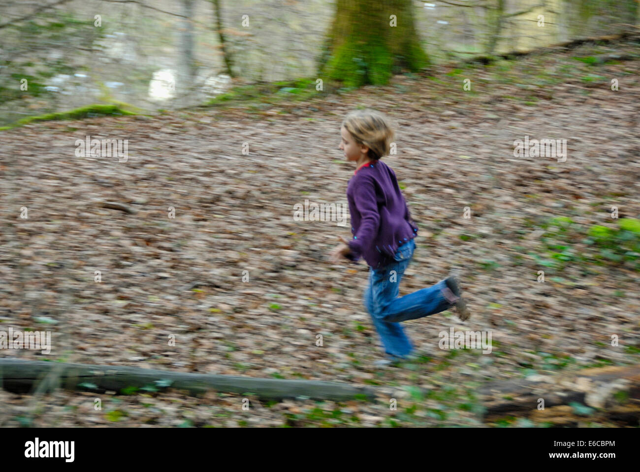 Little girl running through a forest (blurred motion) Stock Photo