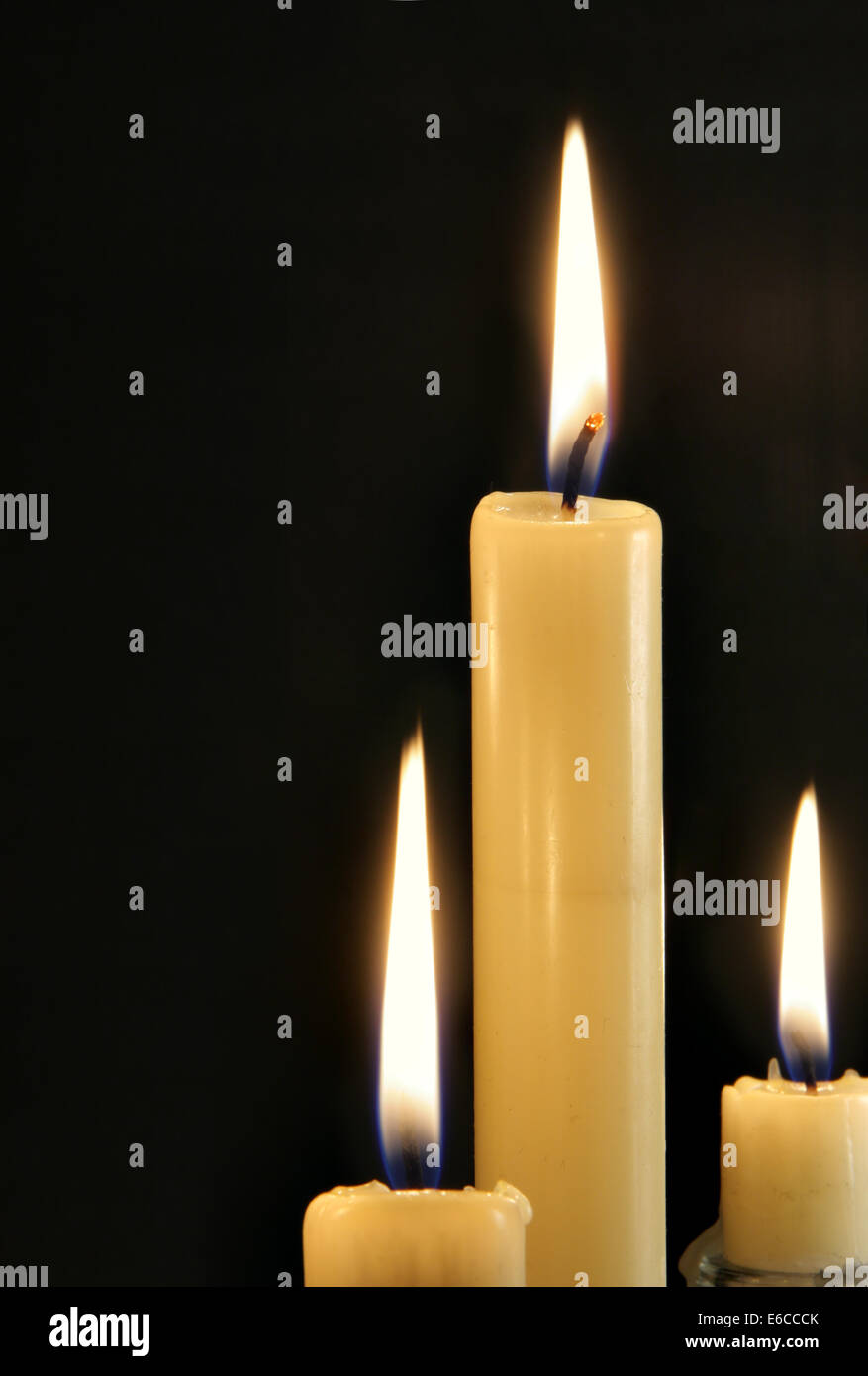 Three burning candles close-up over black background Stock Photo - Alamy