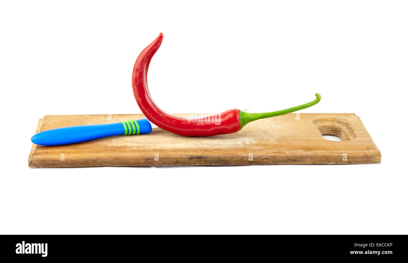 red pepper, steel knife and wooden board, all isolated on white Stock Photo