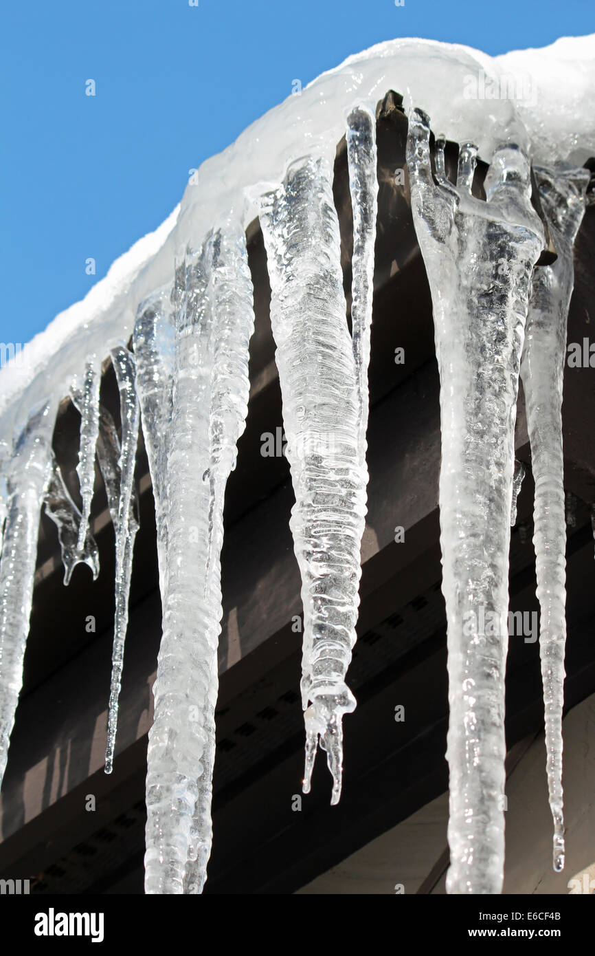 Icicles hanging off a roof in the sunlight Stock Photo