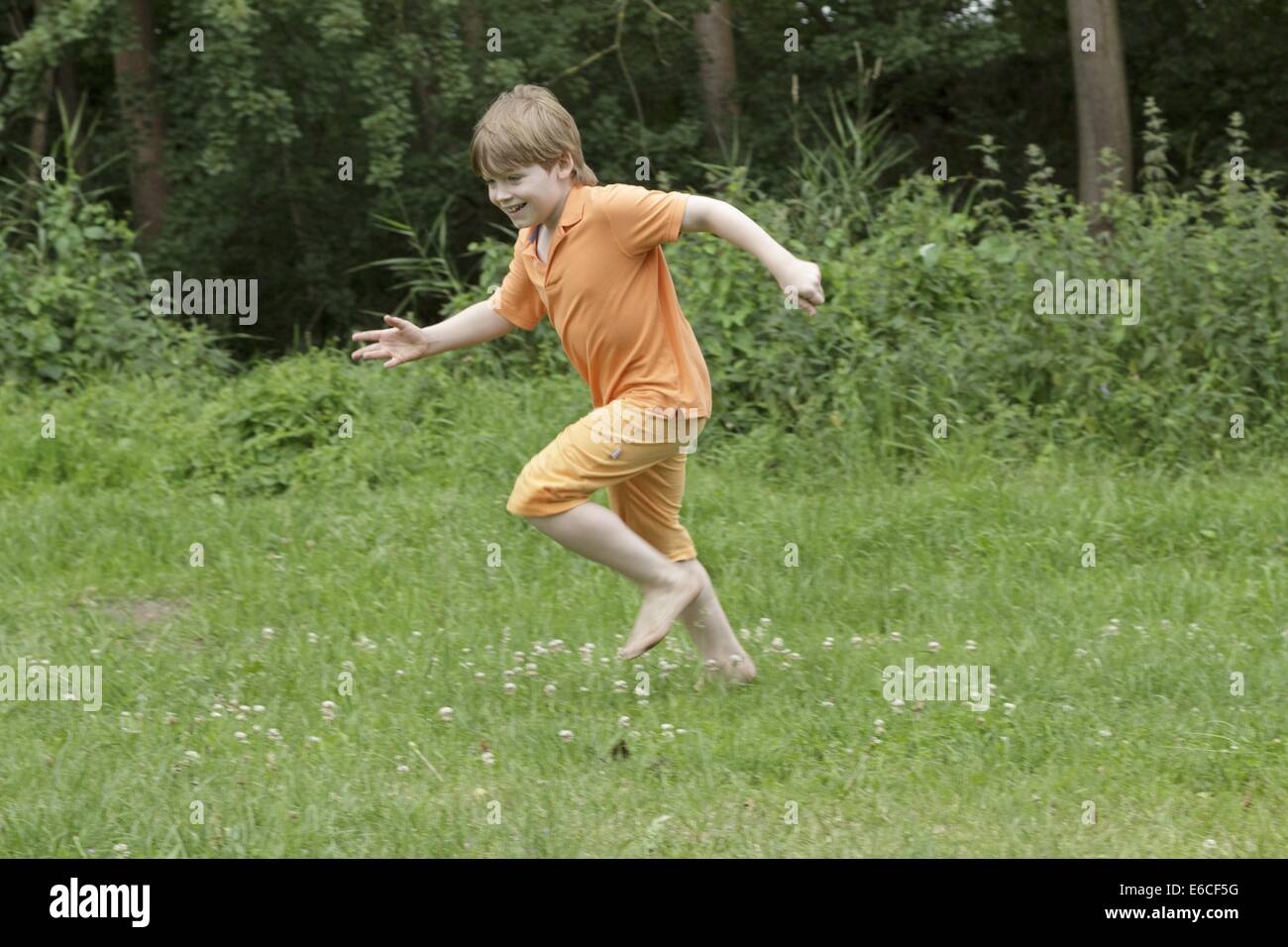 young boy running barefoot across a meadow Stock Photo Alamy