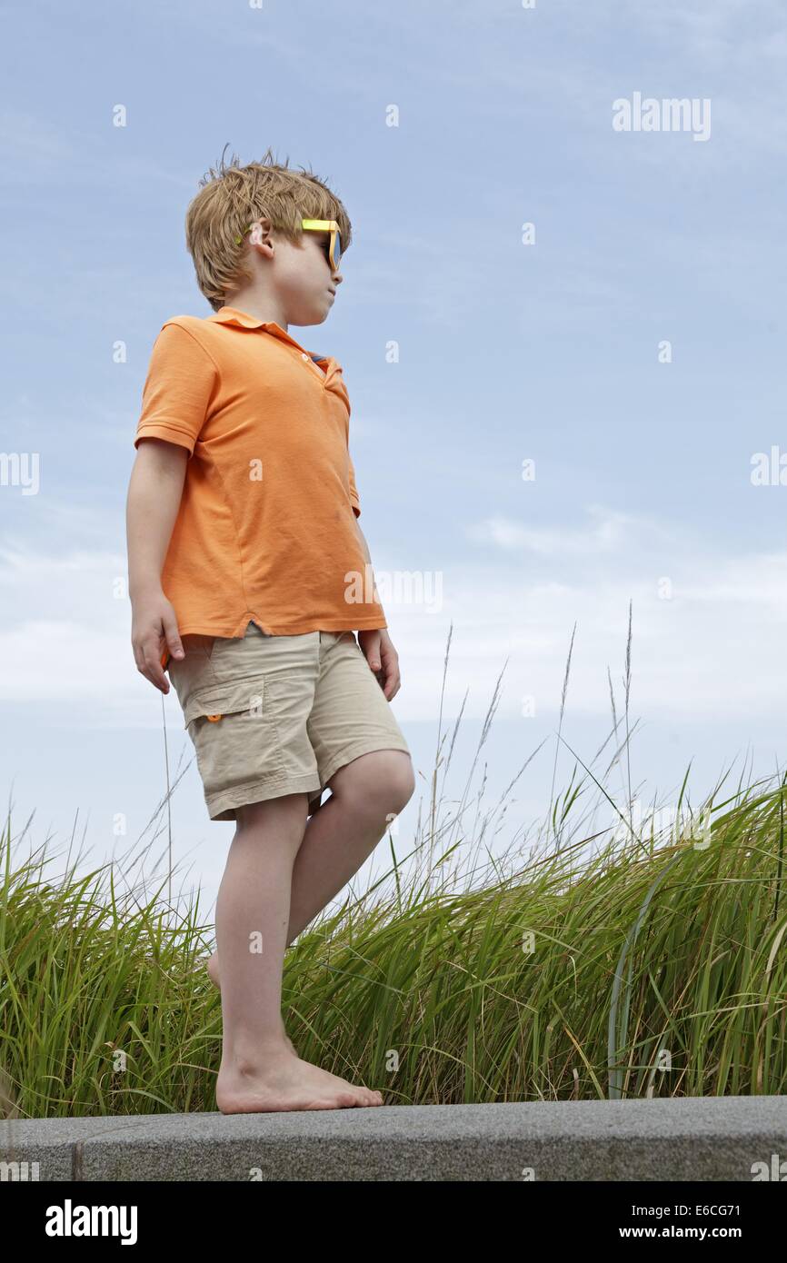 young boy walking barefoot along a wall, Scharbeutz, Baltic Sea, Schleswig-Holstein, Germany Stock Photo