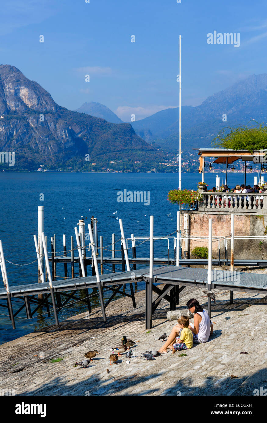 Mother and young son feeding ducks and pigeons on the lakefront in Bellagio, Lake Como, Lombardy, Italy Stock Photo