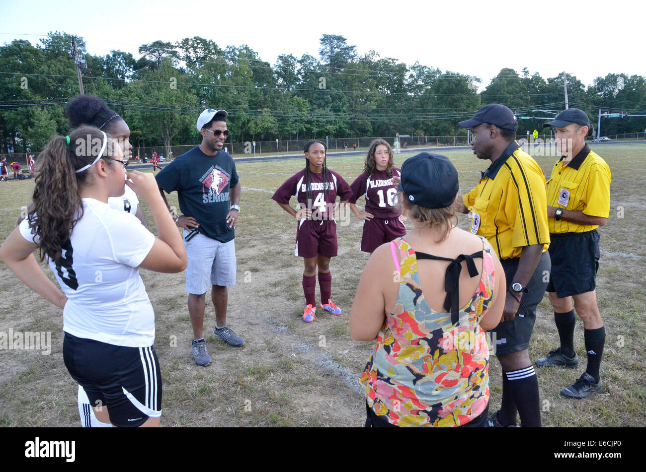 Soccer teams and coaches meet with referees prior to the beginning of a high school soccer game Stock Photo