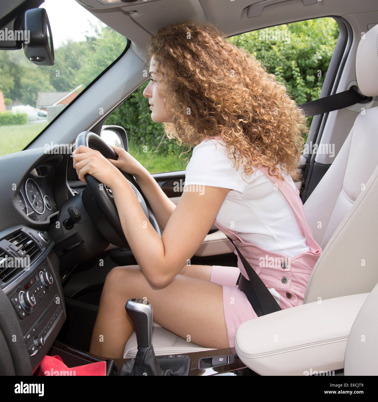 Bad posture and poor driving position. Young female motorist leaning over the steering wheel of a car Stock Photo