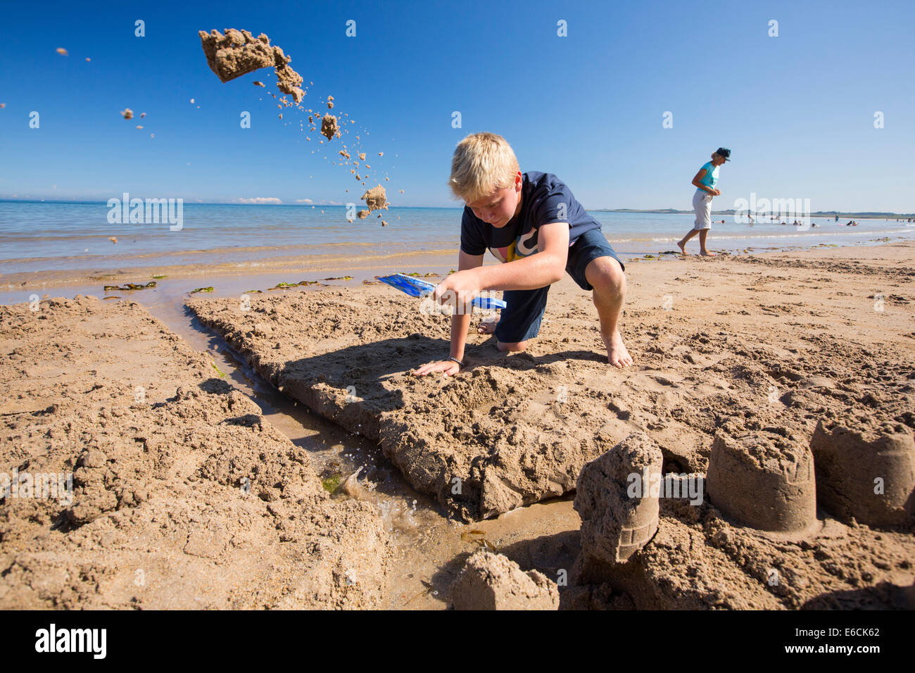 A boy building a sandcastle on Bamburgh Beach, Northumberland, UK. Stock Photo