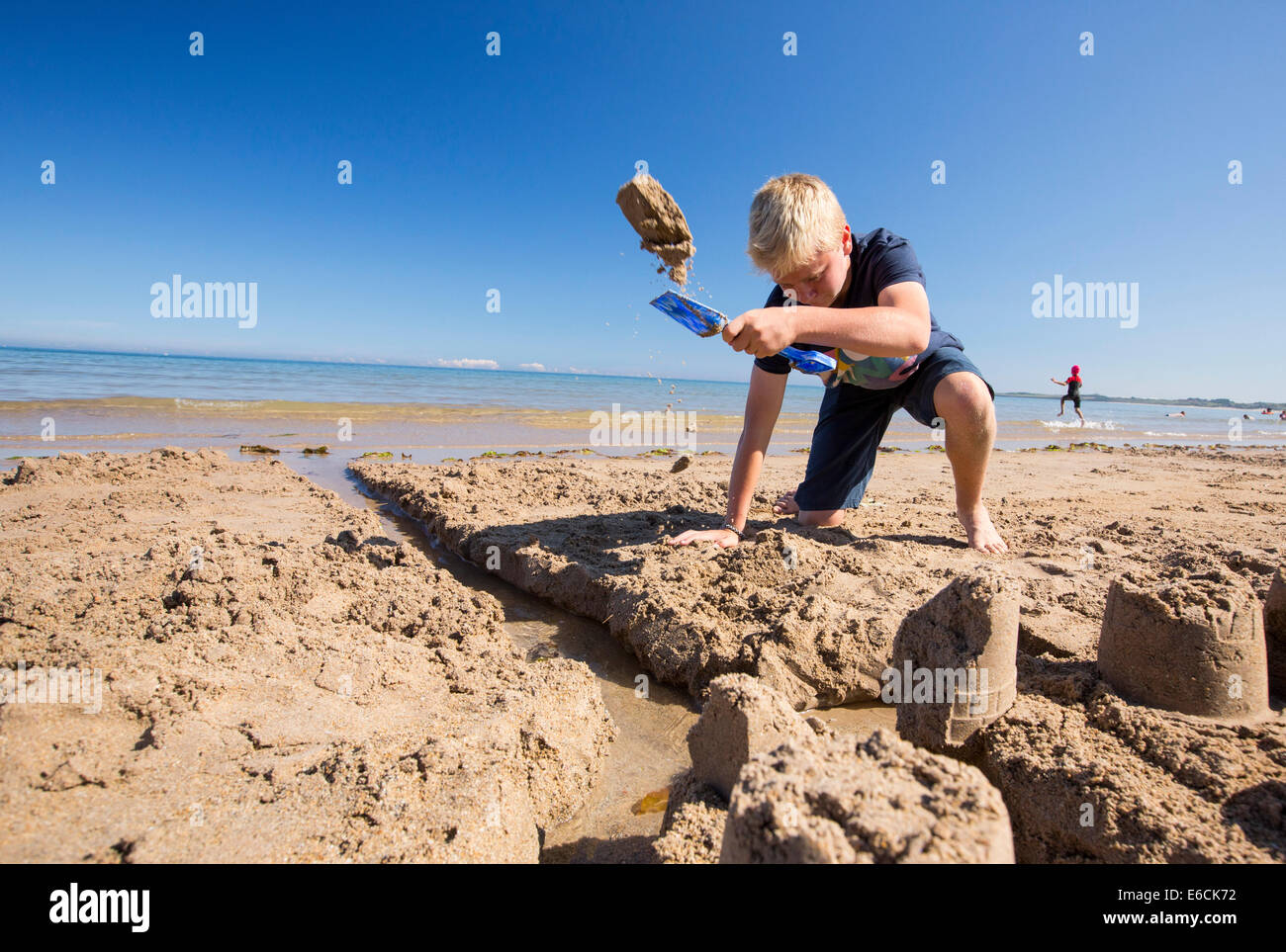 A boy building a sandcastle on Bamburgh Beach, Northumberland, UK. Stock Photo