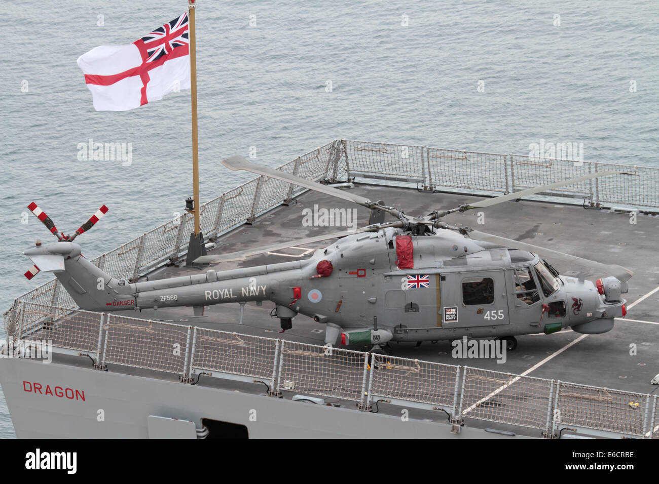 Helicopter on deck of ship. Westland Lynx HMA8 military aircraft on the stern of the Royal Navy destroyer HMS Dragon beneath a flying White Ensign Stock Photo