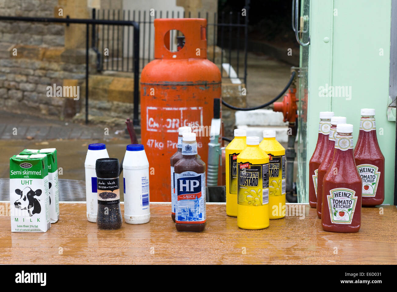 Group of sauces on a table at a burger bar, multiple bottles of ketchup HP Sauce, Mustard, salt