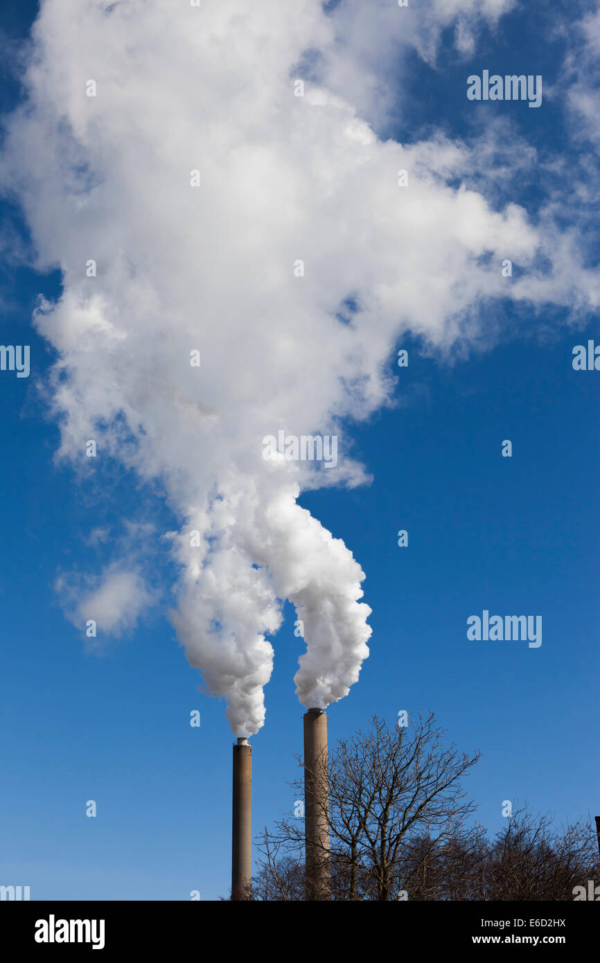 White chimney smoke air pollution with blue sky behind. Stock Photo