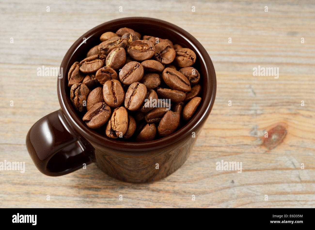 brown cup with coffee beans on wooden background Stock Photo