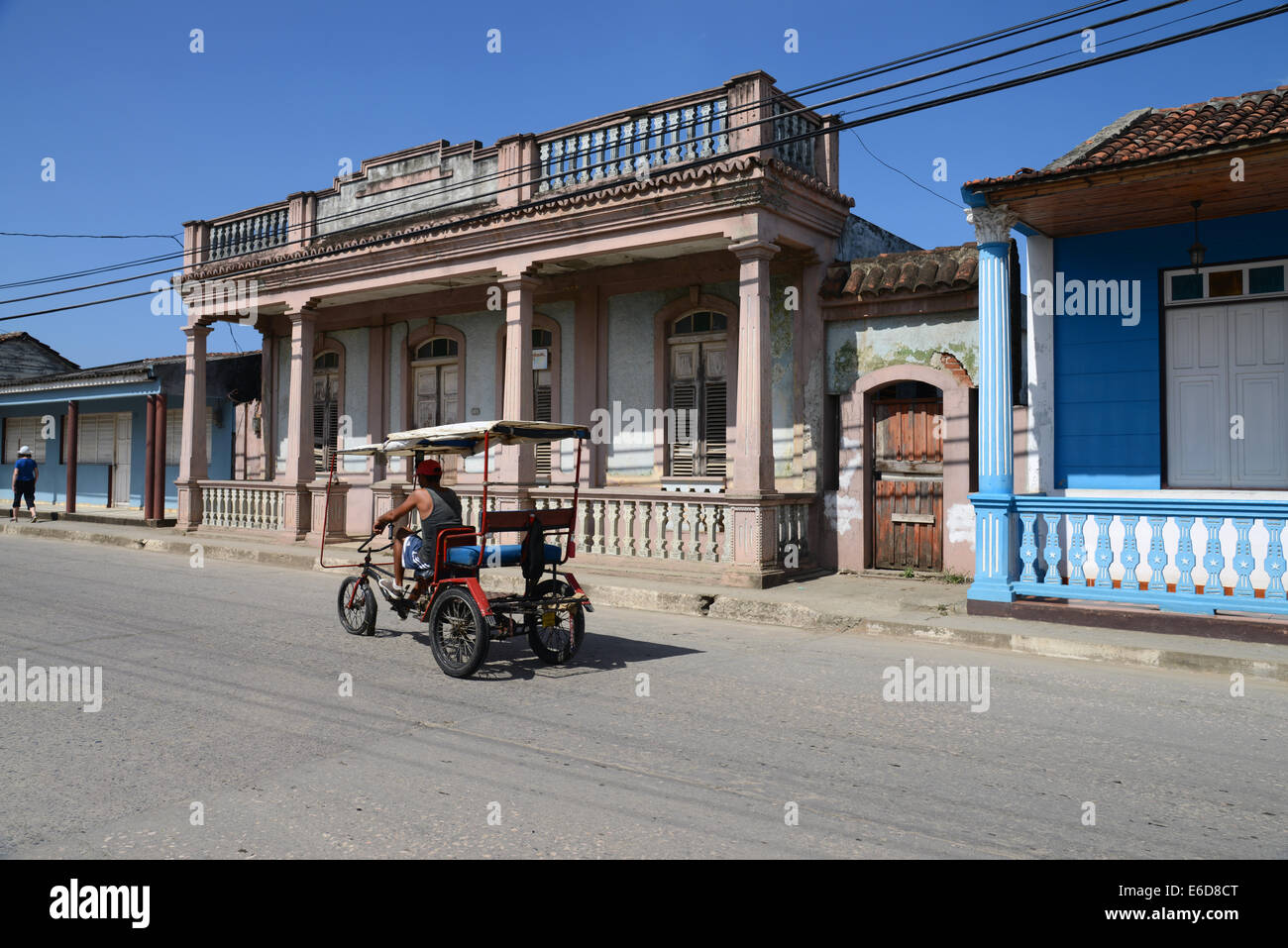 Typical ricksaw-style bicycle taxi in main street in Baracoa, eastern Cuba, in front of a typical oldcoonial-style building. Stock Photo