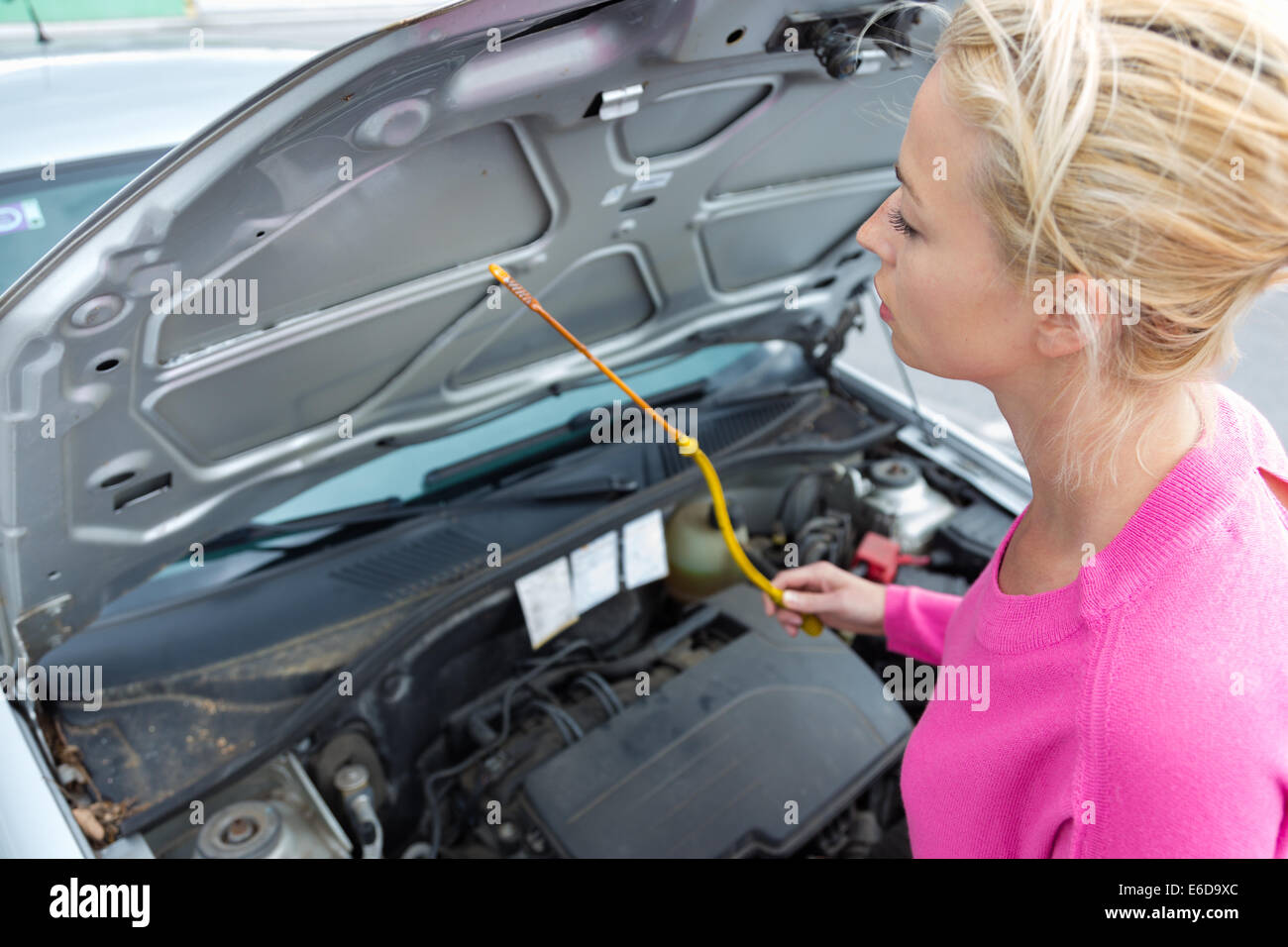 Woman inspecting broken car engine. Stock Photo