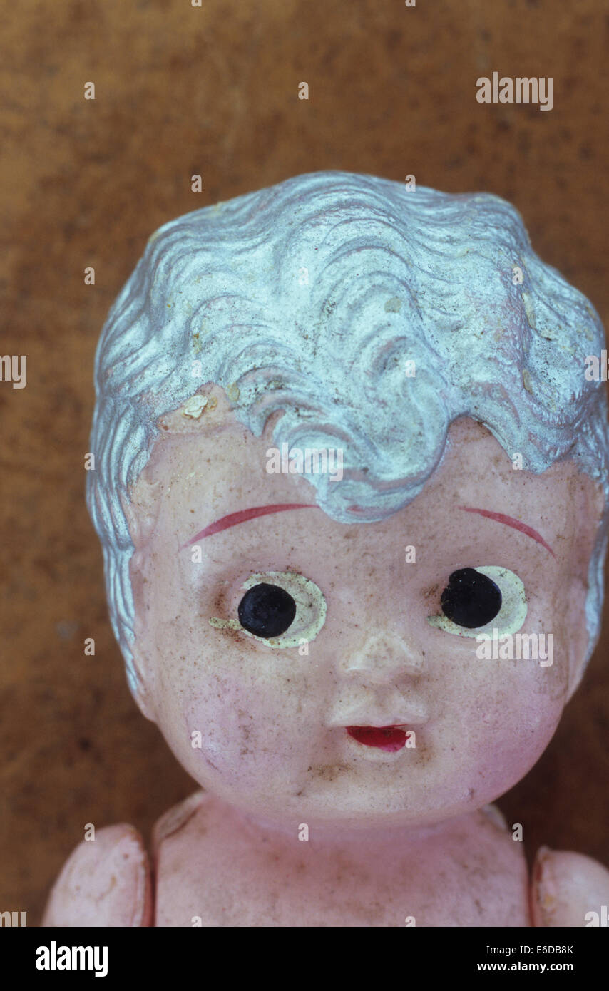Head of soiled vintage celluloid girl doll with silver painted hair and worried expression Stock Photo