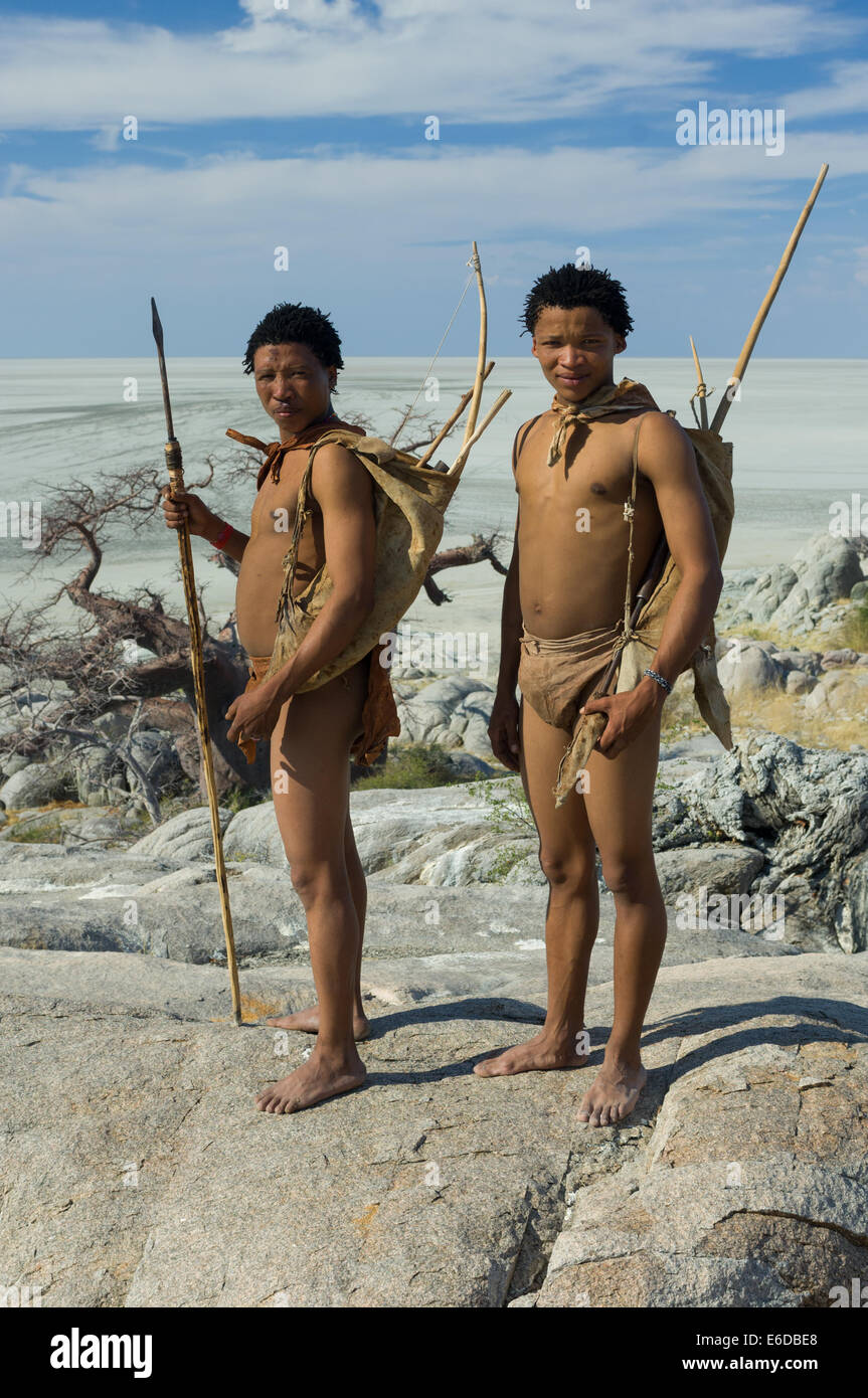 San Bushmen standing on the granite mass of Kubu Island (Lekhubu), with the expanse of the Makgadikgadi Pan behind, Botswana Stock Photo