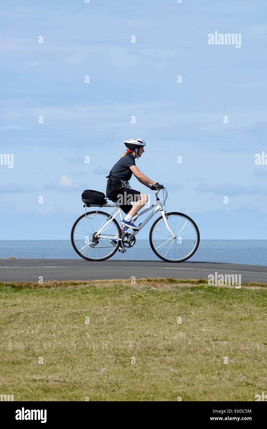 Woman riding bicycle on coastal path in Blackpool, Lancashire Stock Photo