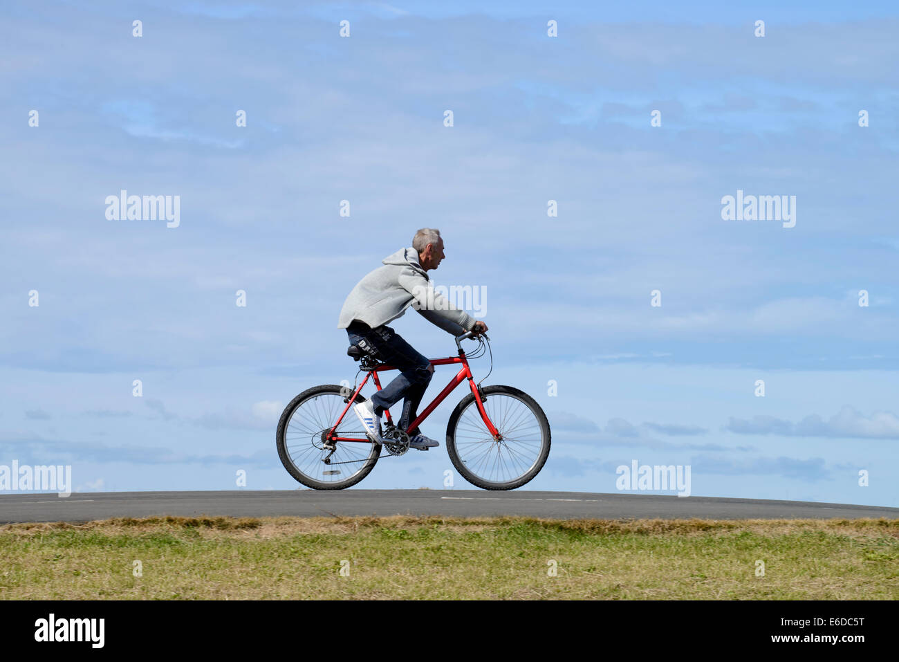 Man riding bicycle on coastal path in Blackpool, Lancashire Stock Photo