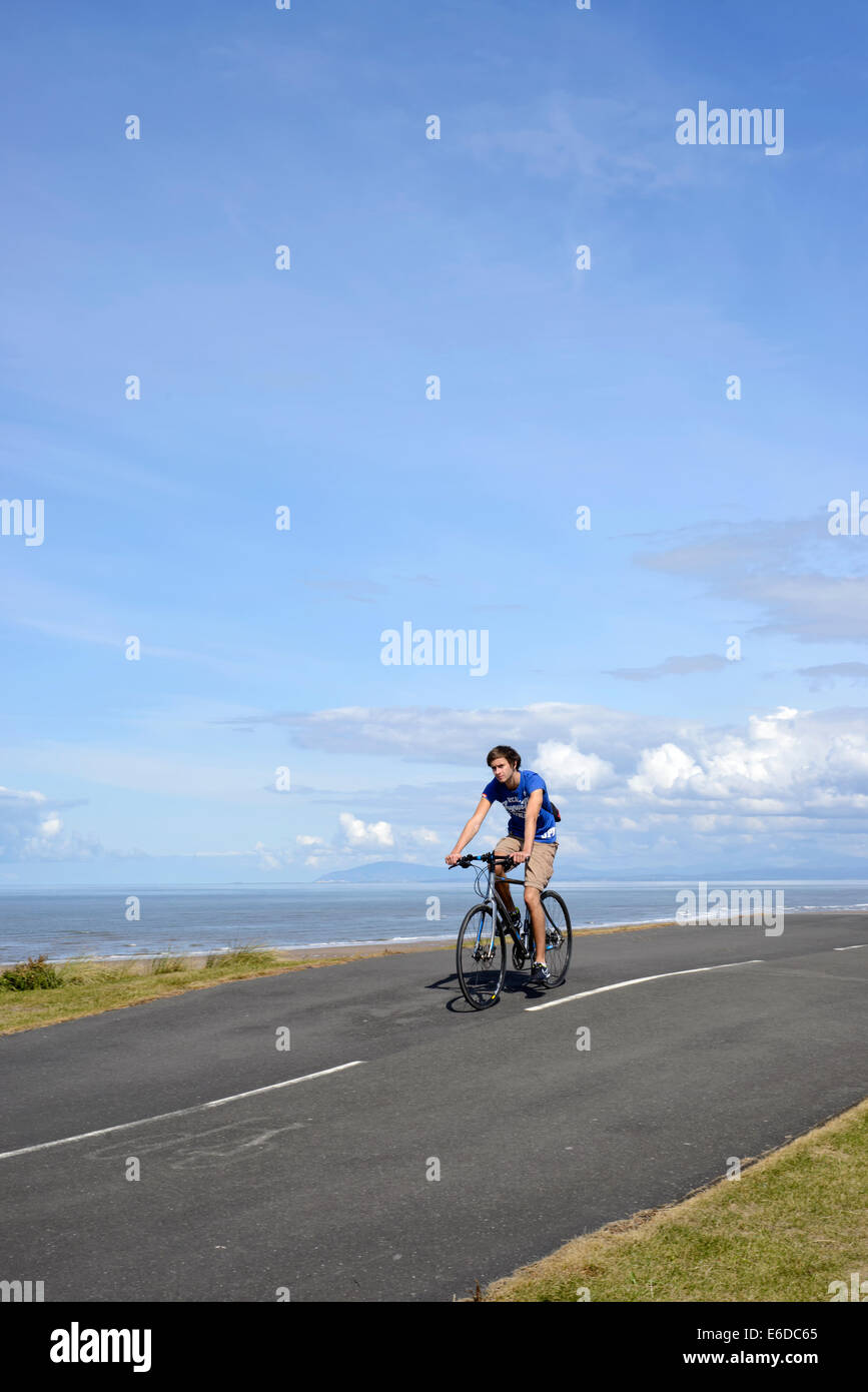 Young man riding bicycle on coastal path in Blackpool, Lancashire Stock Photo