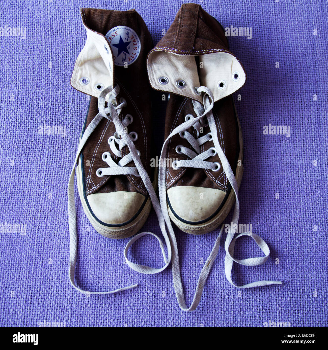 Brown converse all-star boots on lilac background with laces spelling 'love'. Stock Photo
