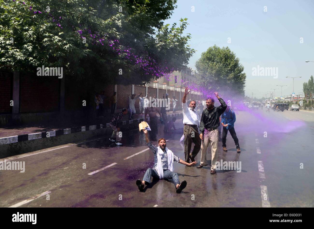 Srinagar, Indian-controlled Kashmir. 21st Aug, 2014. Kashmiri government employees shout slogans as Indian police spray color water during a protest demanding regularization of their jobs in Srinagar, summer capital of Indian-controlled Kashmir, Aug. 21, 2014. Credit:  Javed Dar/Xinhua/Alamy Live News Stock Photo
