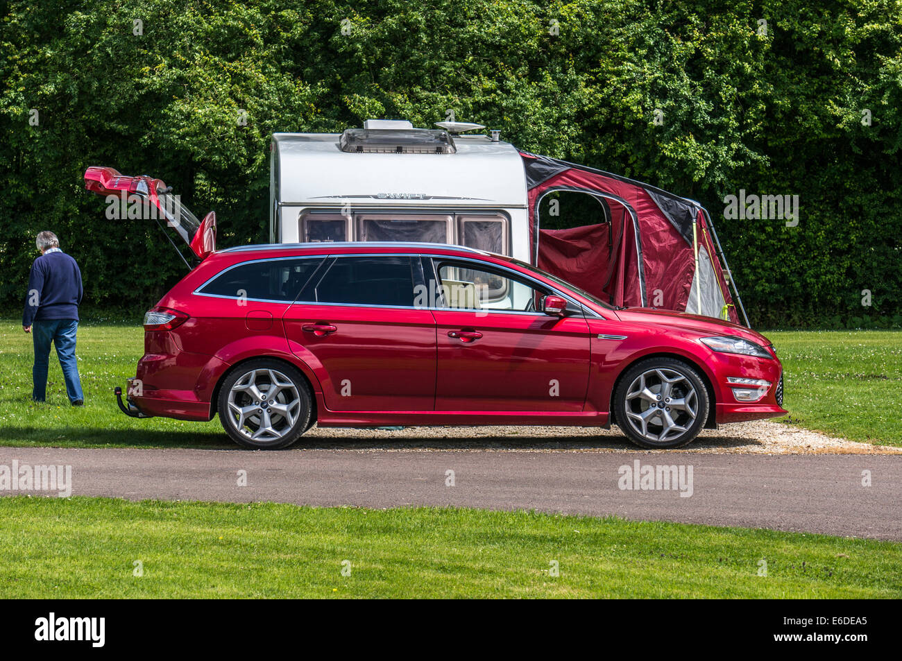 An elderly / old / senior  lady walking away from her caravan and car on a Caravan Club campsite pitch in England, UK. Stock Photo