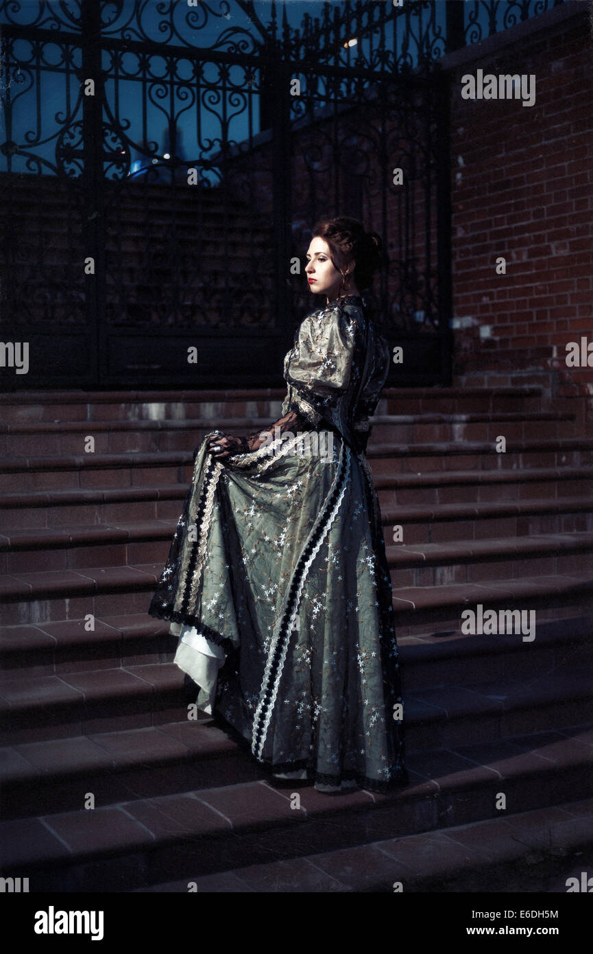 Russian 19th century young woman posing on the stairs in twilight Stock Photo