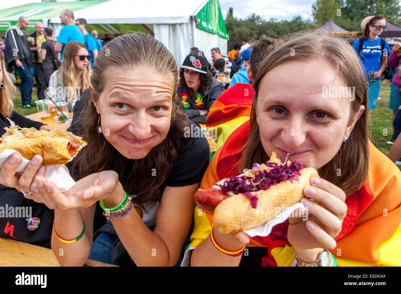 Two girls eat Hotdogs from fast food, sausage in a bun with mustard, People eating food Prague Letna Park, Czech Republic unhealthy eating Stock Photo
