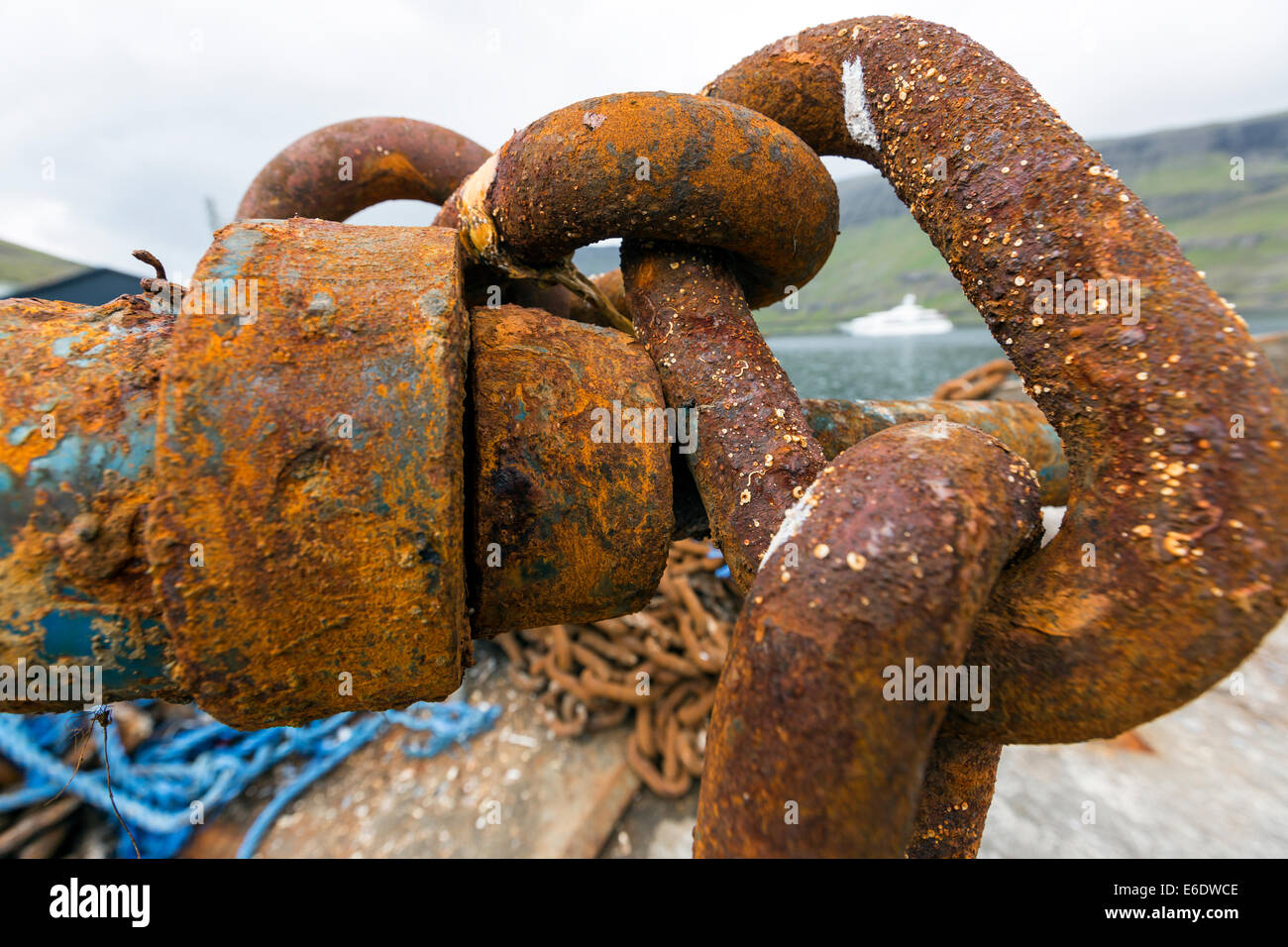 Rusty anchor chain knot and the yacht Vive La Vie owned by Willy Michel