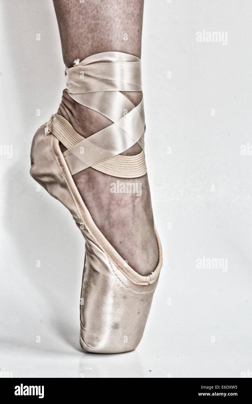 Legs of a ballerina with a black high heel shoe in one feet and a