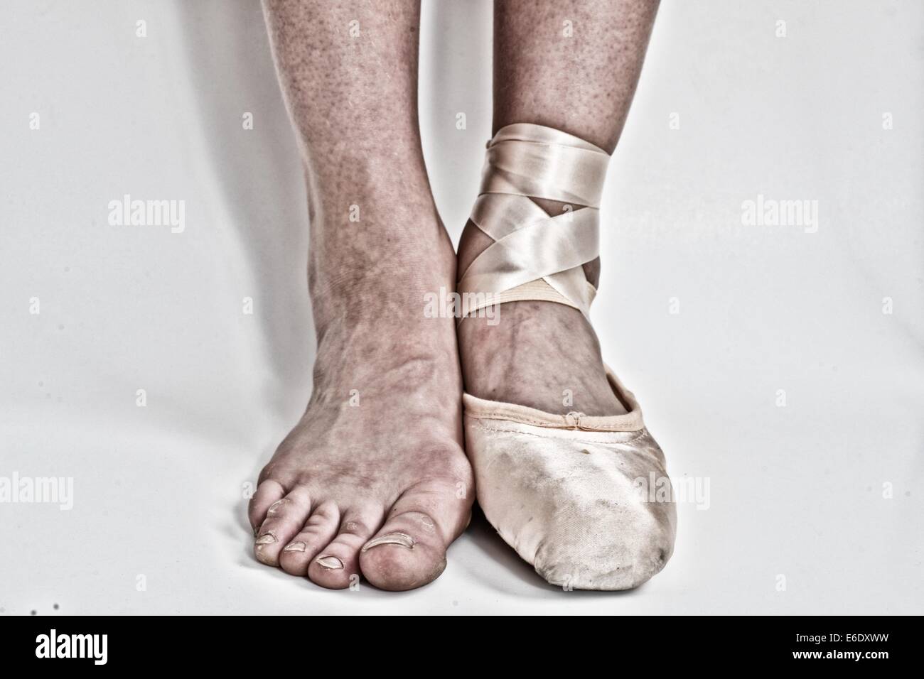 Feet of a ballerina, one with a ballet pointe shoe and the other barefoot. Stock Photo