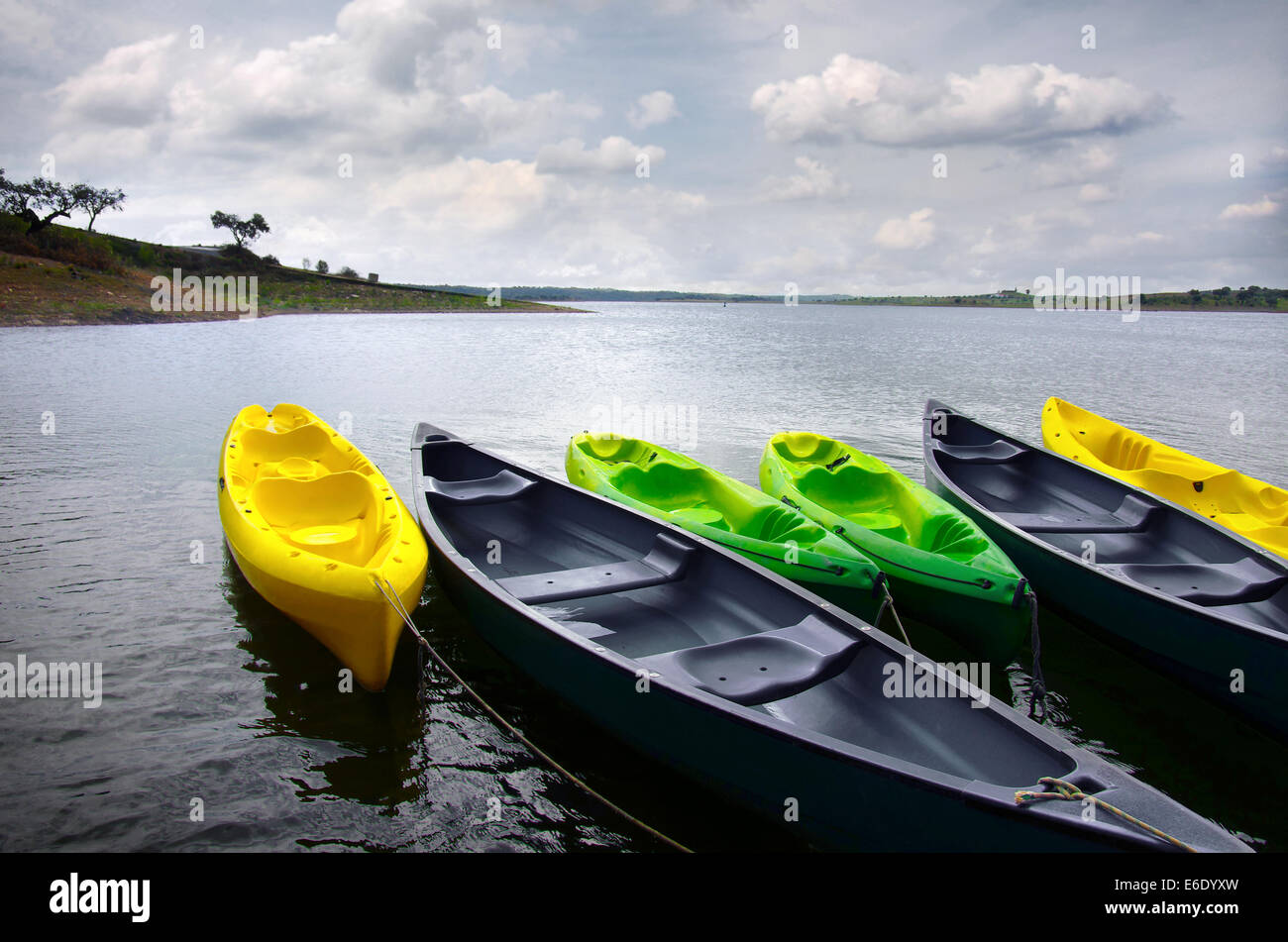 Green and yellow kayaks and canoes docked in the shore of a lake Stock Photo