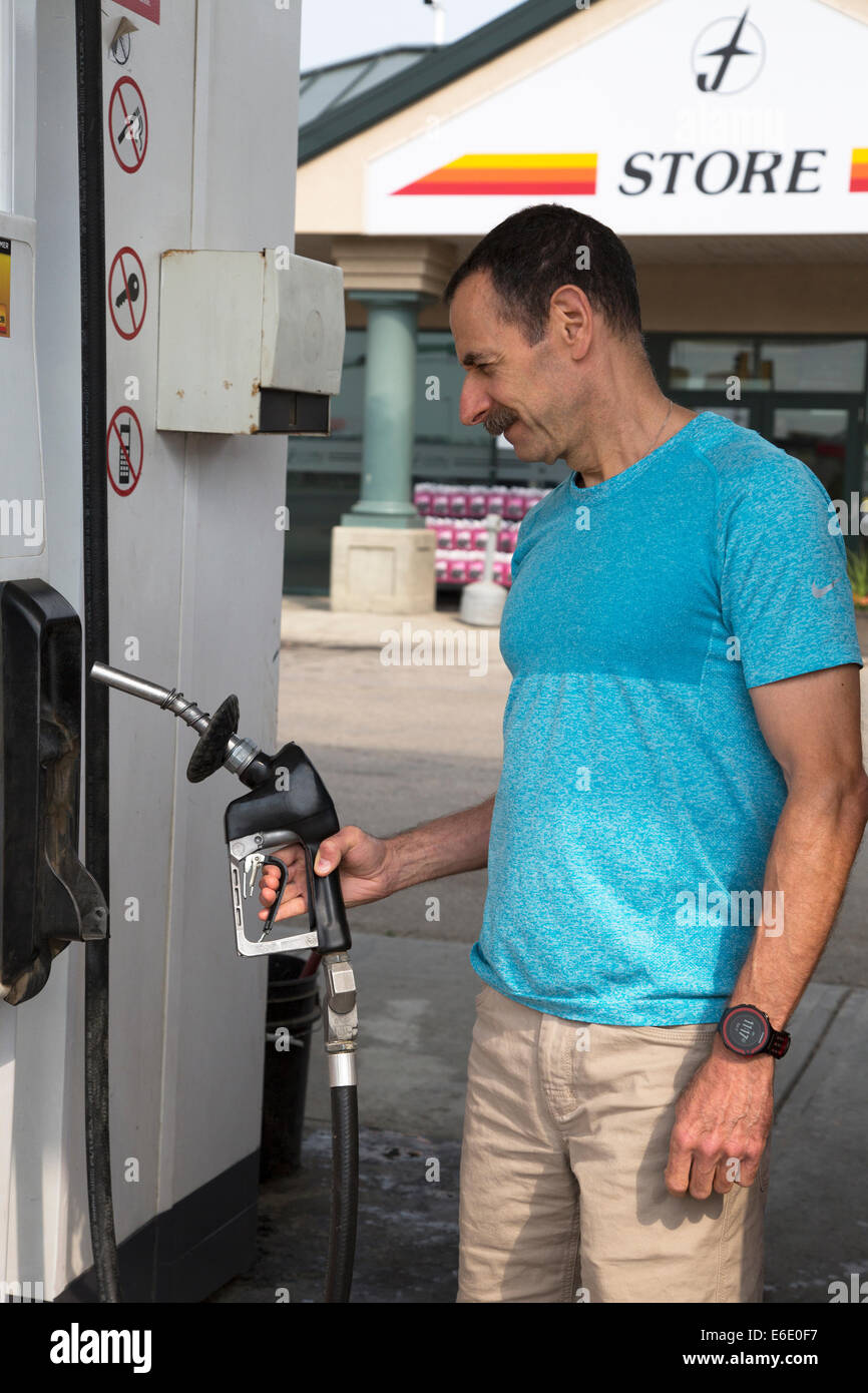 Man lifting gas pump nozzle to refuel at service station. Stock Photo