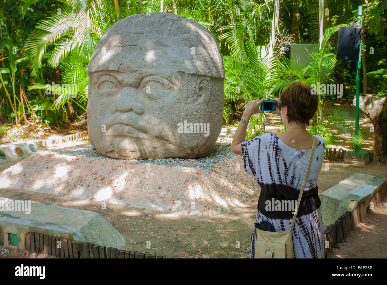 A tourist photographs the Olmec stone carving named Colossal Head in La Venta Park in Villahermosa, Tabasco, Mexico. Stock Photo