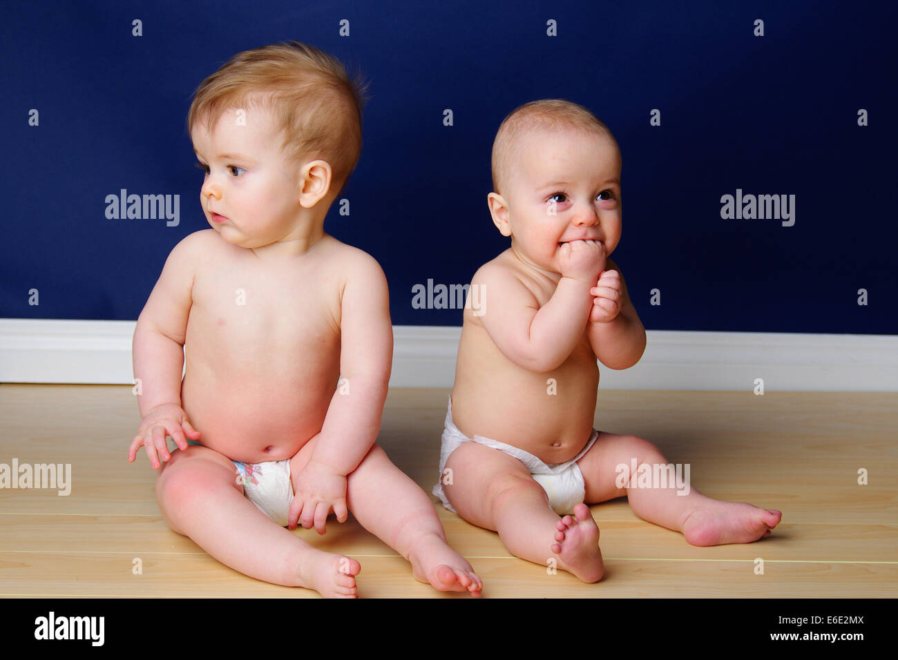Twin 9 month old babies grinning and sitting up Stock Photo
