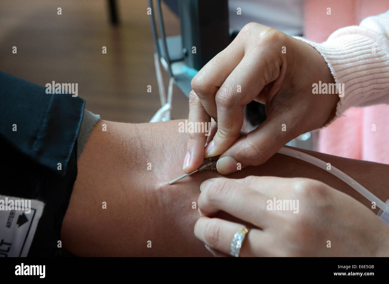 Medical officer inserting syringe into man's arm for blood donation Stock Photo