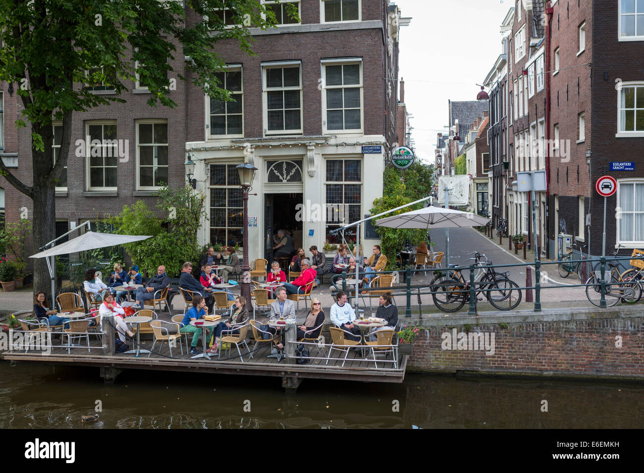 Tourists relaxing at café bar ' 't Smalle' at the famous old neighborhood ' the Jordaan' along a canal at Amsterdam. Stock Photo