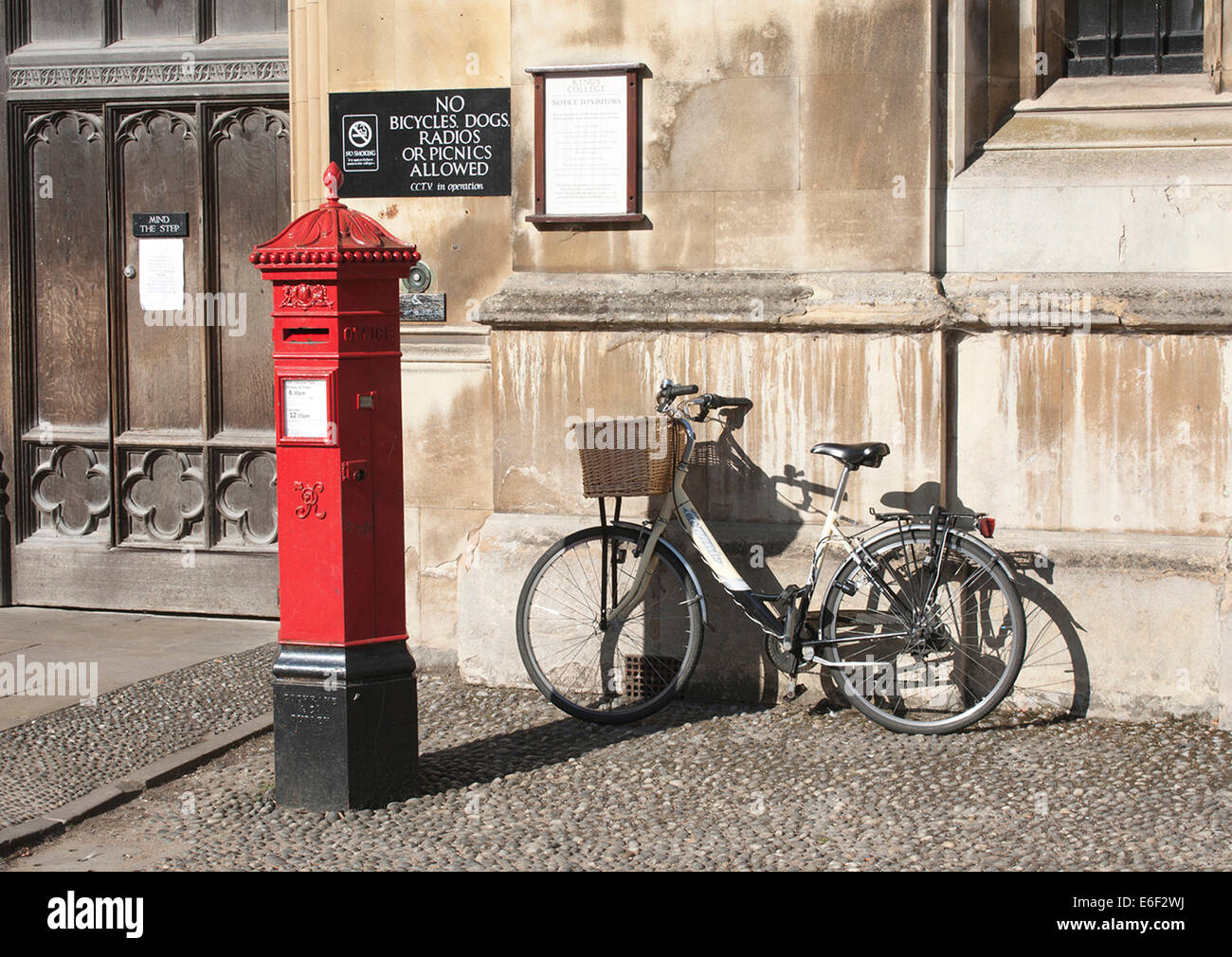 Victorian postbox with bicycle outside Kings College University, Cambridge. Stock Photo
