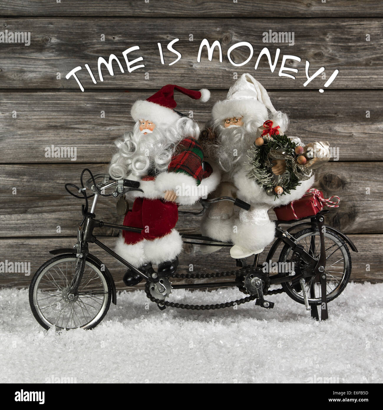 Time is money -  santa claus team in rush for buying christmas presents. Funny photo in vintage style with an old tandem bike of Stock Photo