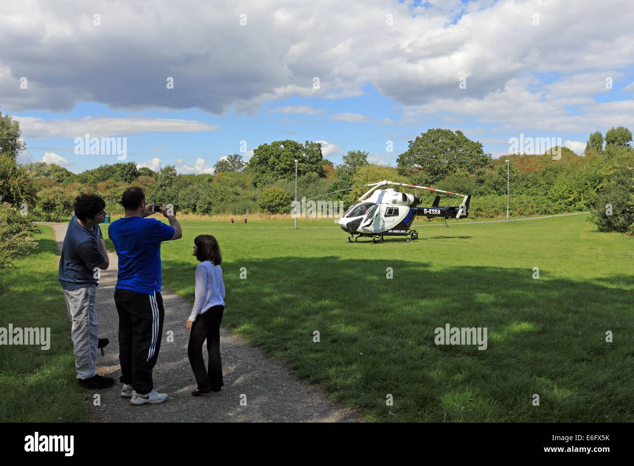 West Ewell, Epsom, Surrey, UK. 22nd Aug, 2014. Residents of West Ewell had a suprise this afternoon as the KSSA (Kent Surrey Sussex Air ambulance) landed on an area of the Hogsmill Open Space between Riverview School and the Watersedge Estate. It landed at 13.30 in response to 'A medical Emergency' on the estate. Locals gathered to see the unusual site of a helicopter so close to nearby housing, and as it was summer holiday time many curious childern were keen to witness the event. Credit:  Julia Gavin UK/Alamy Live News Stock Photo