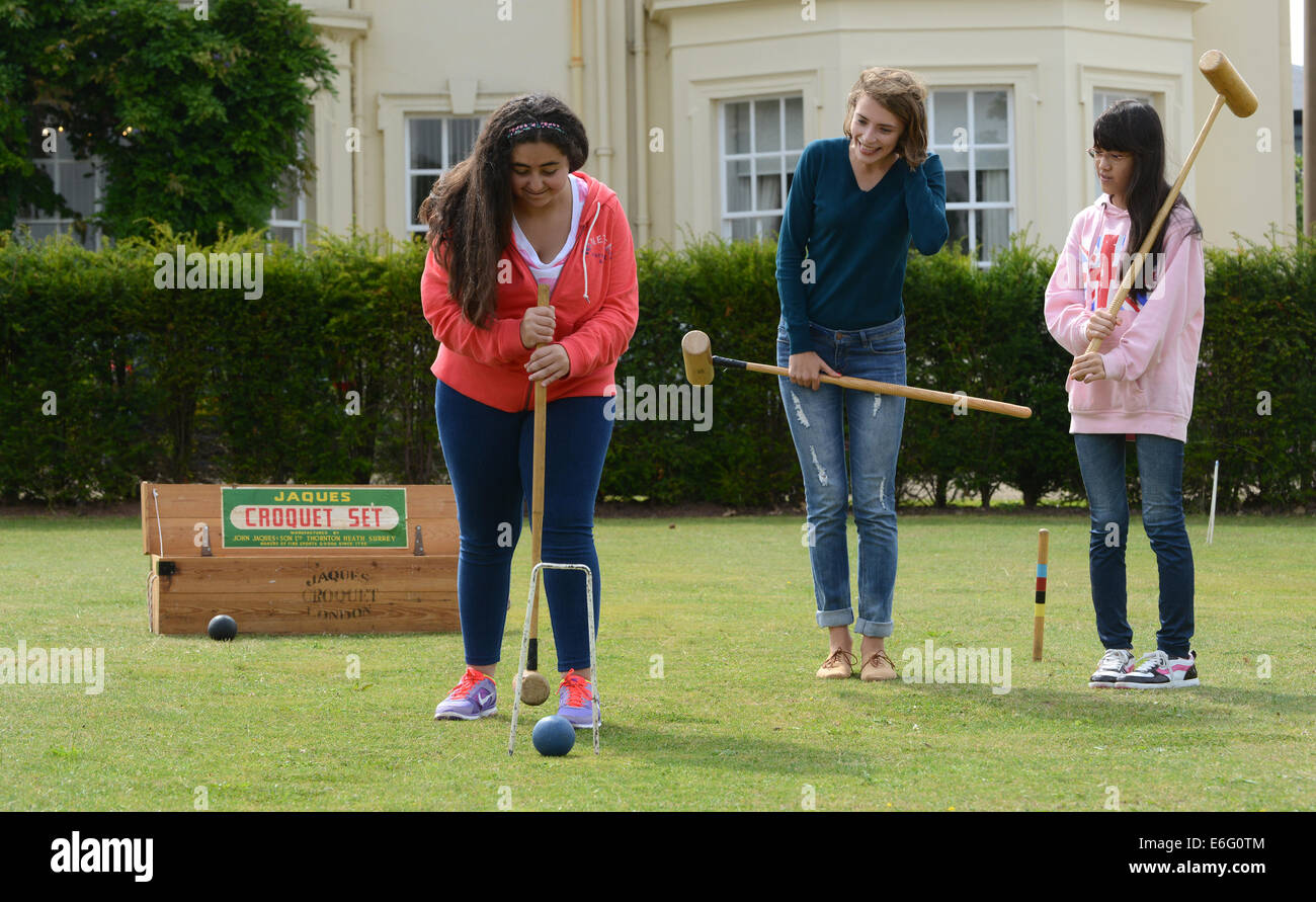 Concord College at Acton Burnell Foreign students learning Croquet LtoR Amina Sharif (Saudi Arabia) plays watched by Olga Blinova (Russia) and Eleanor Ueda (Japan). Stock Photo