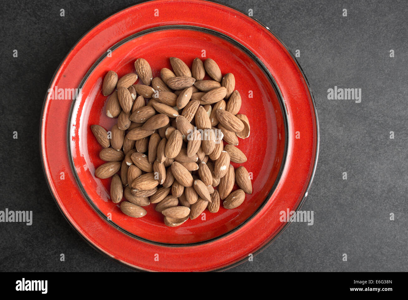 Raw almonds in red plate, from above Stock Photo Alamy