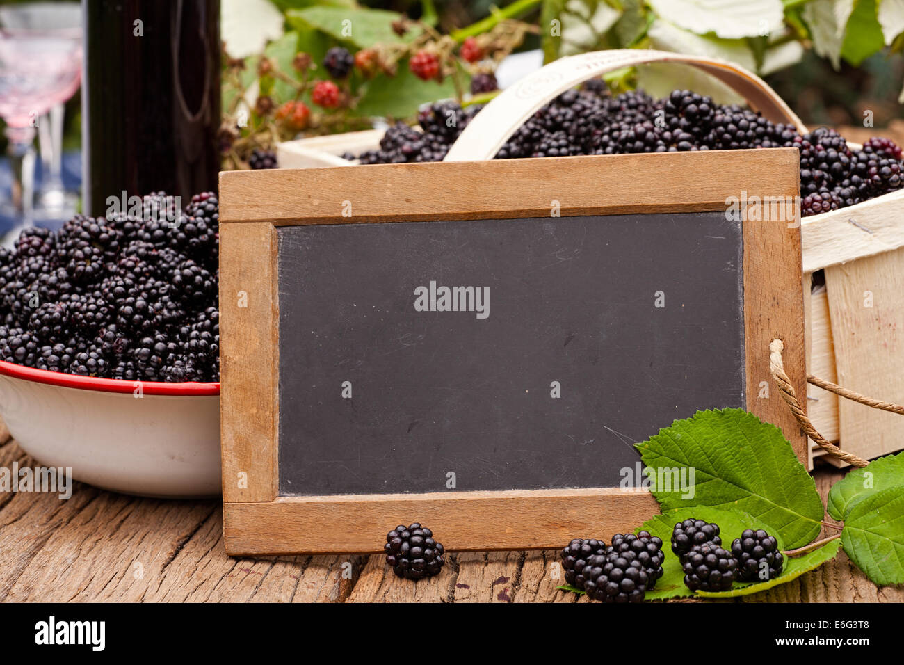 Blank advertising space on a slate blackboard in front of ripe blackberries on a rustic wooden table Stock Photo