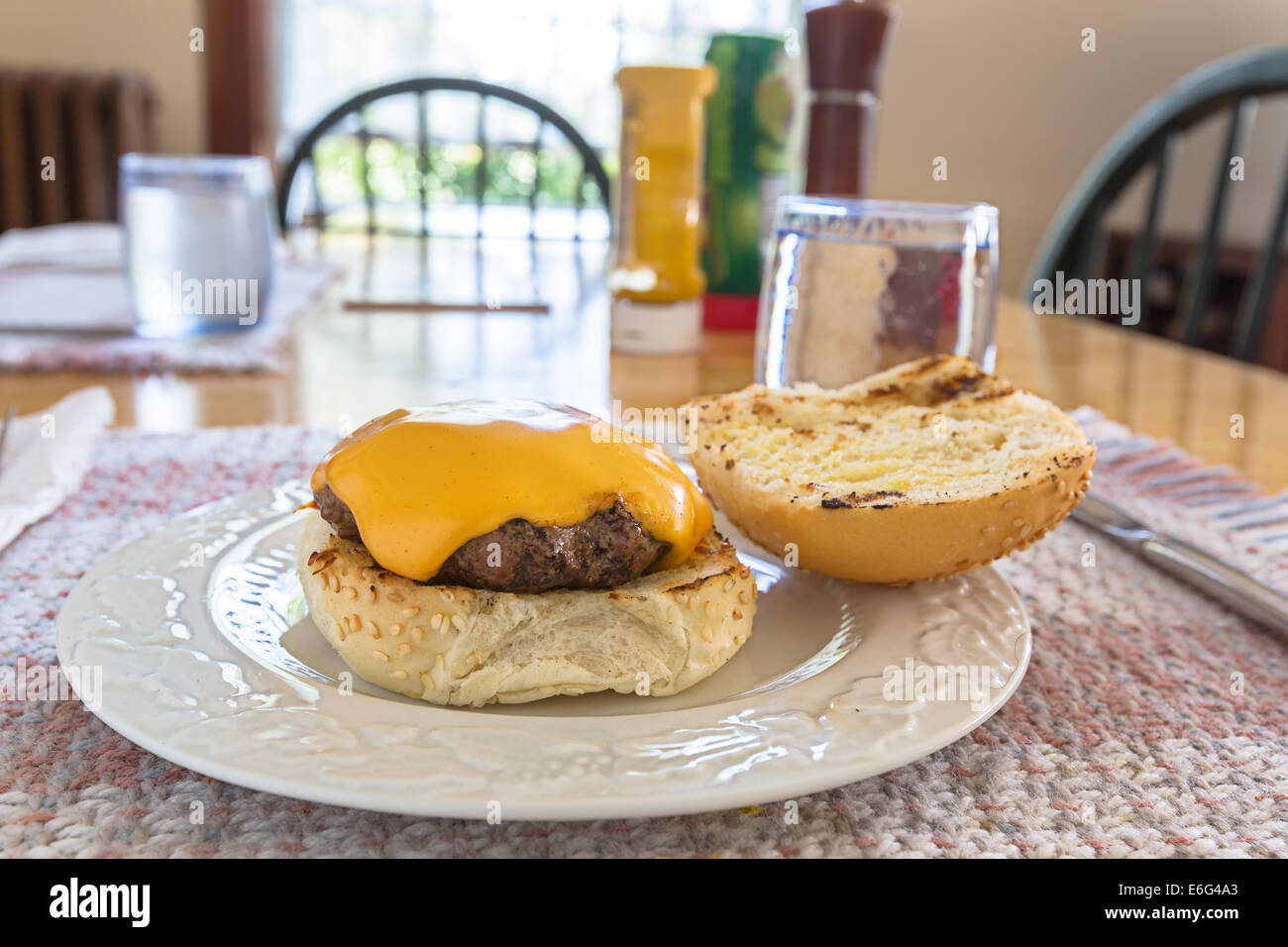 Delicious homemade hamburgers with cheese at the kitchen table. Stock Photo