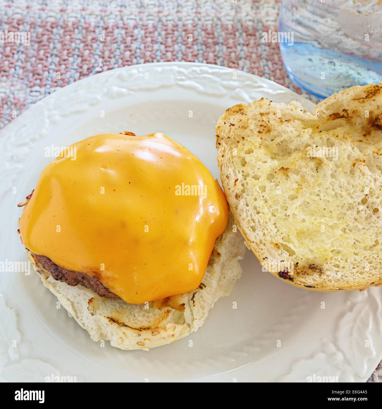 Delicious homemade hamburger with cheese at the kitchen table. Stock Photo